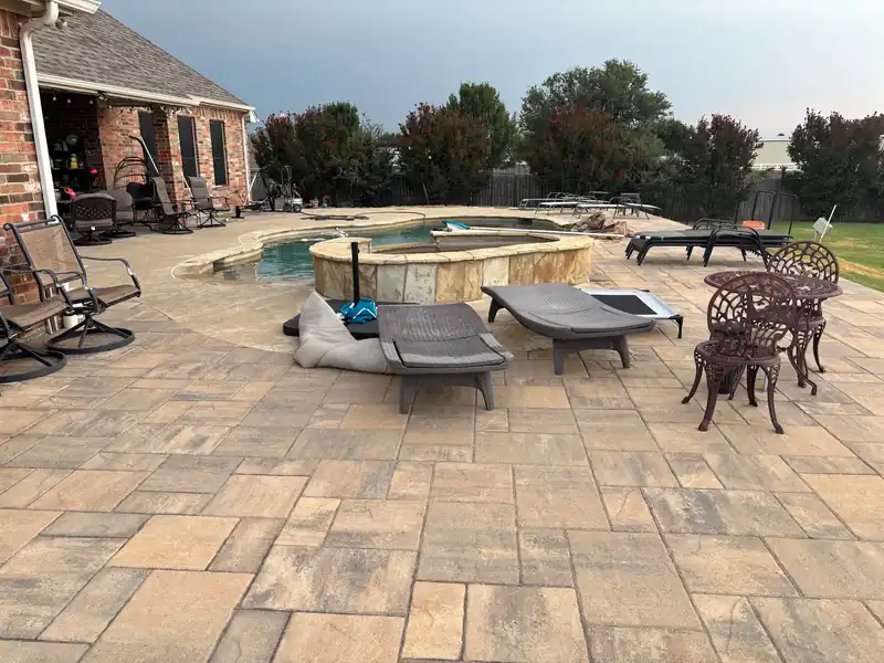 Multi-tone paver patio and raised stone spa built around a client's pool